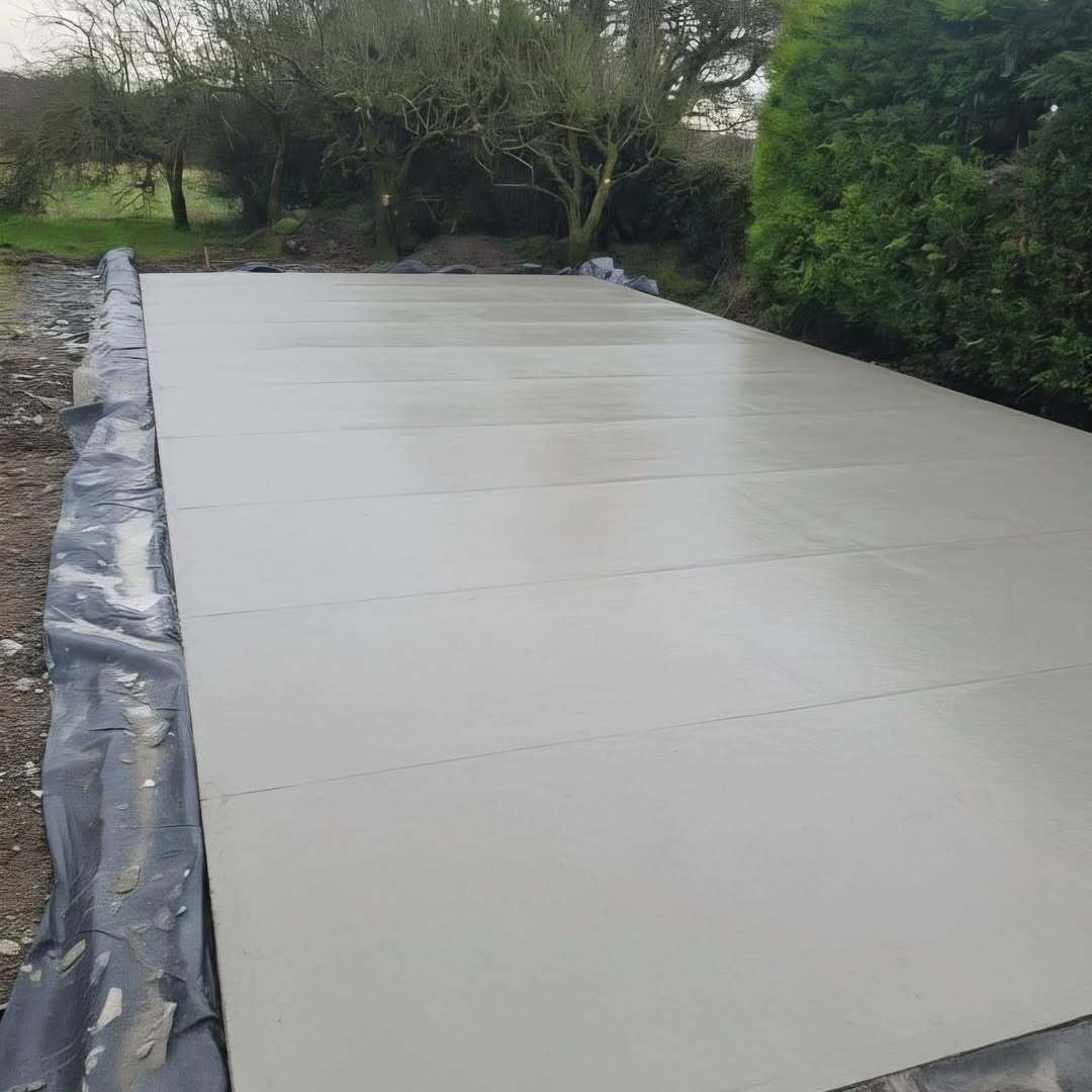 Finished residential concrete slab with a smooth surface finish beside a garden hedge in Trim